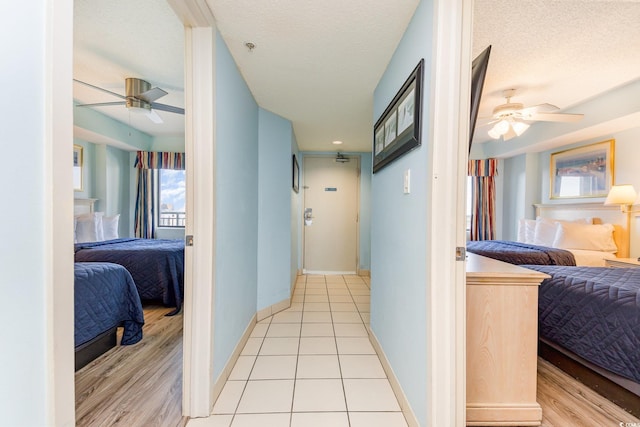 hall featuring light tile patterned floors and a textured ceiling