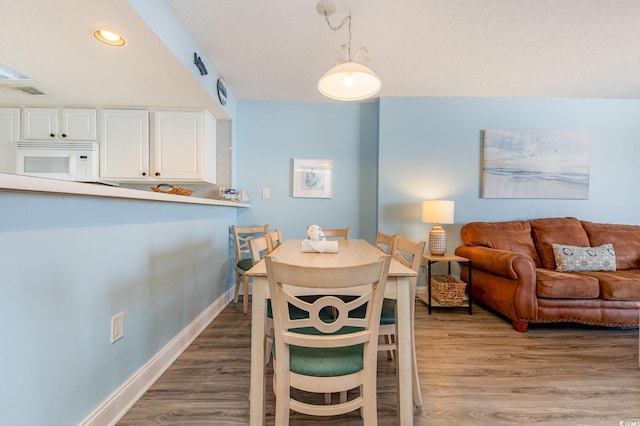 dining area with wood-type flooring and a textured ceiling