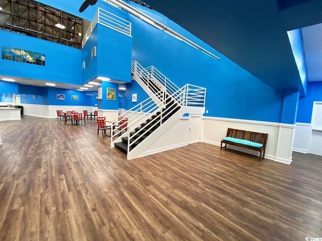 unfurnished living room featuring wood-type flooring, ceiling fan, and a high ceiling