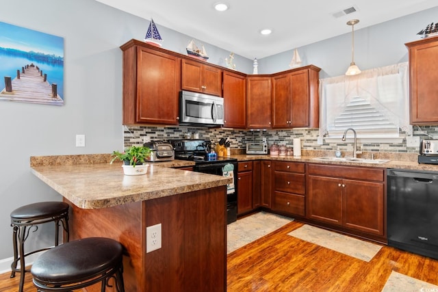 kitchen featuring black appliances, tasteful backsplash, visible vents, and a sink