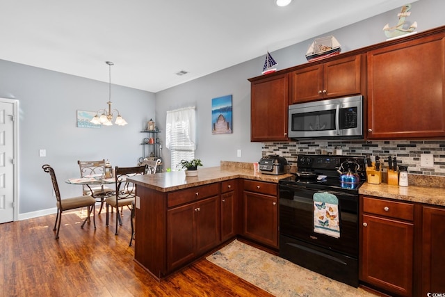 kitchen featuring dark wood-style floors, black electric range, stainless steel microwave, and a peninsula