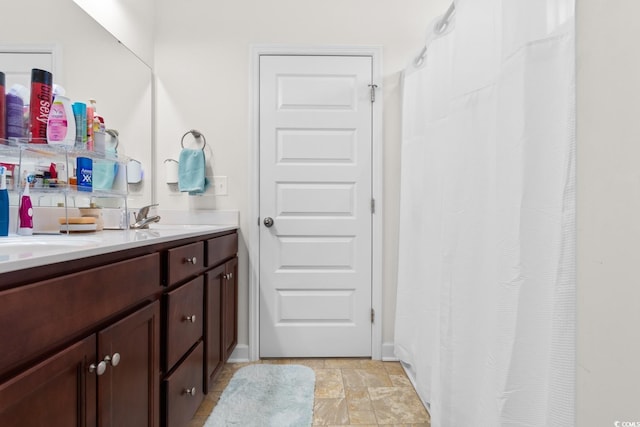 bathroom featuring double vanity, stone finish floor, a shower with shower curtain, and a sink