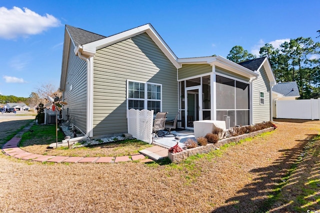 rear view of property with a sunroom, a patio area, fence, and a lawn