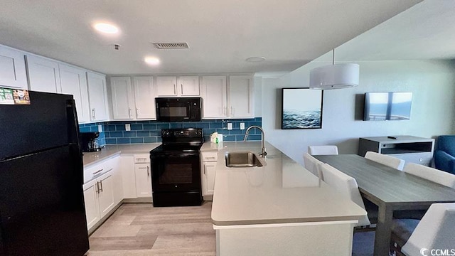 kitchen featuring sink, black appliances, light hardwood / wood-style flooring, white cabinets, and backsplash