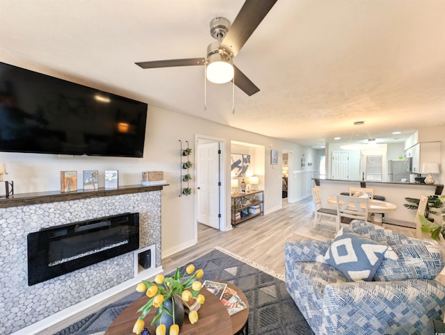 living room with ceiling fan, a fireplace, and light hardwood / wood-style flooring