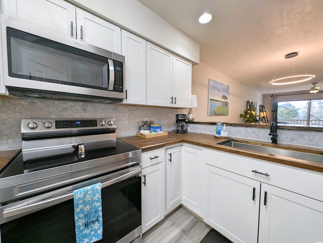 kitchen with stainless steel appliances, sink, wooden counters, and white cabinets