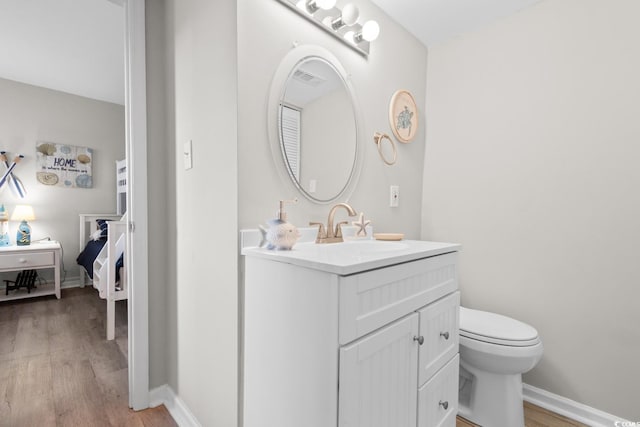 bathroom featuring vanity, wood-type flooring, and toilet