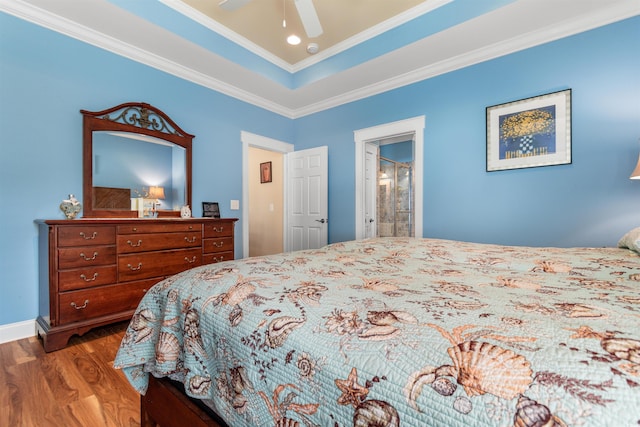 bedroom with crown molding, ceiling fan, hardwood / wood-style floors, ensuite bathroom, and a raised ceiling