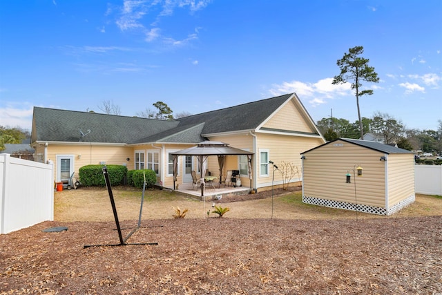 rear view of property featuring a shed, a gazebo, and a patio