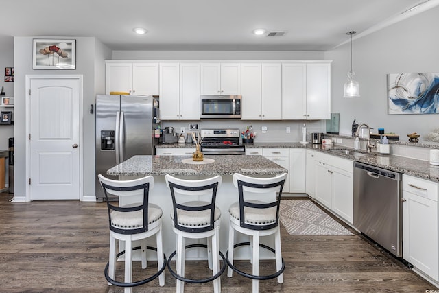 kitchen with white cabinetry, stainless steel appliances, kitchen peninsula, and hanging light fixtures