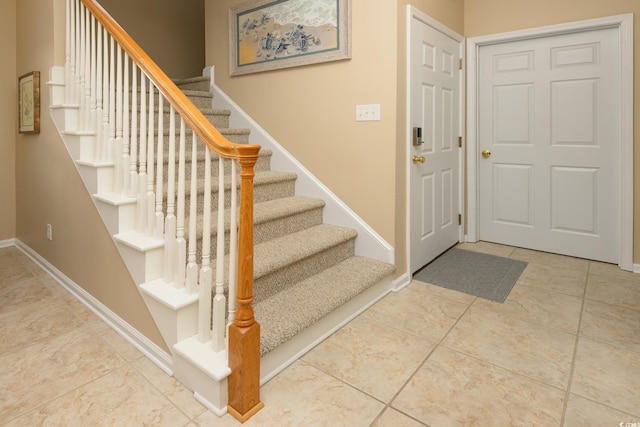 tiled entrance foyer with baseboards and stairs