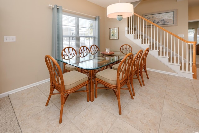 dining area with light tile patterned floors, baseboards, and stairway