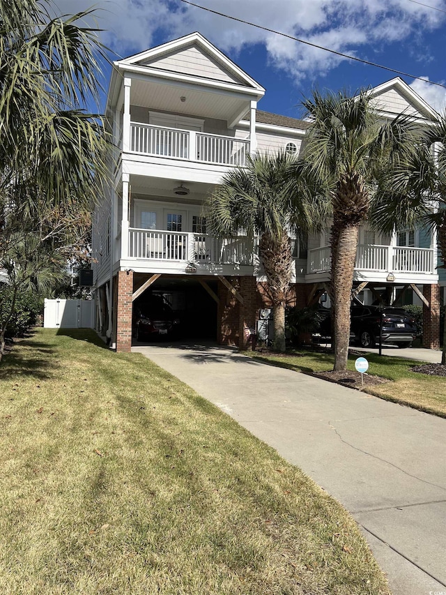 raised beach house with a front yard, a carport, and a balcony