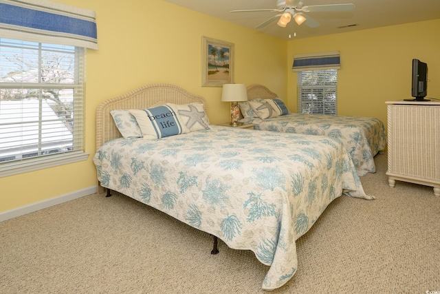 carpeted bedroom with ceiling fan, multiple windows, and baseboards