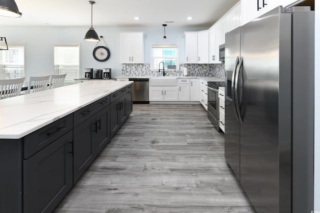 kitchen featuring pendant lighting, white cabinetry, sink, decorative backsplash, and stainless steel appliances