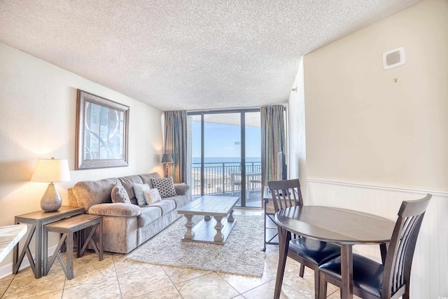 living room featuring floor to ceiling windows, a water view, light tile patterned floors, and a textured ceiling