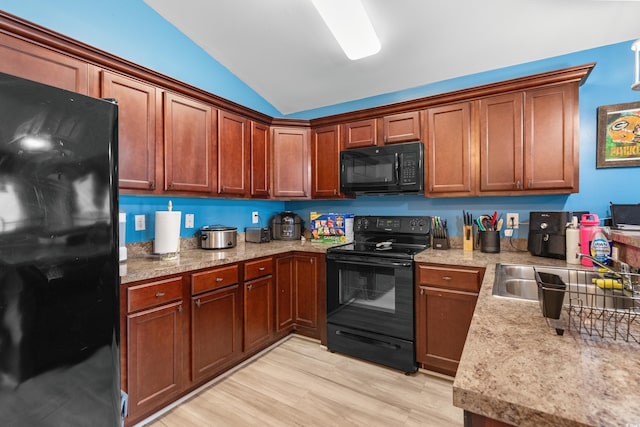 kitchen featuring vaulted ceiling, sink, light wood-type flooring, and black appliances