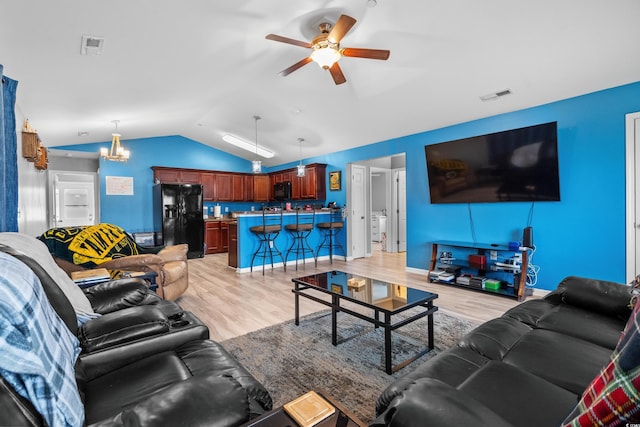 living room with ceiling fan with notable chandelier, vaulted ceiling, and light wood-type flooring