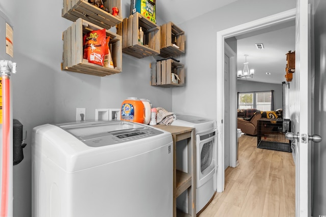 laundry room with an inviting chandelier, washer and clothes dryer, and light wood-type flooring