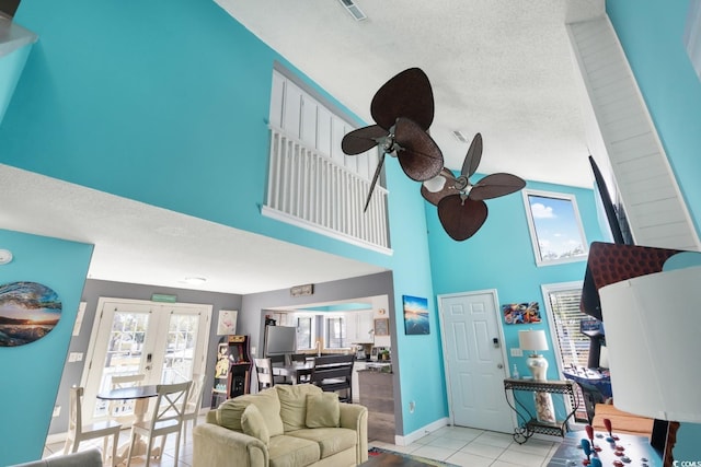 living room featuring light tile patterned flooring, ceiling fan, a textured ceiling, and french doors