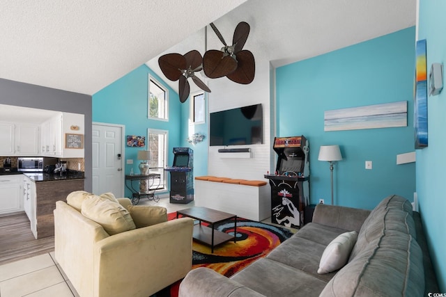 living room featuring light tile patterned floors, a textured ceiling, high vaulted ceiling, and ceiling fan