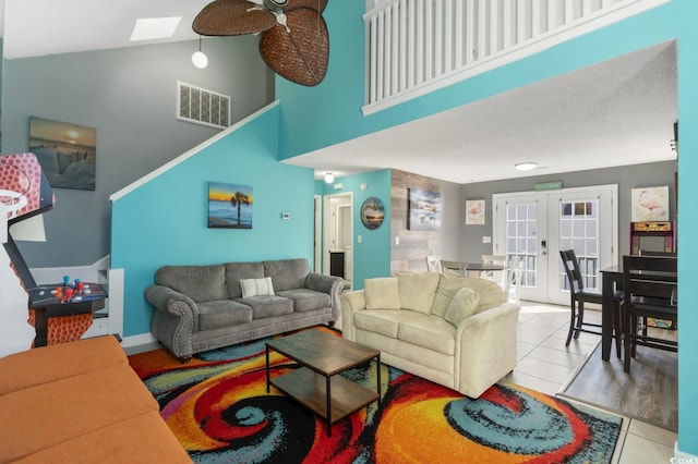 tiled living room with a skylight, high vaulted ceiling, french doors, and ceiling fan