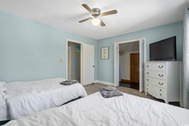 bedroom with hardwood / wood-style flooring, ceiling fan, and a textured ceiling