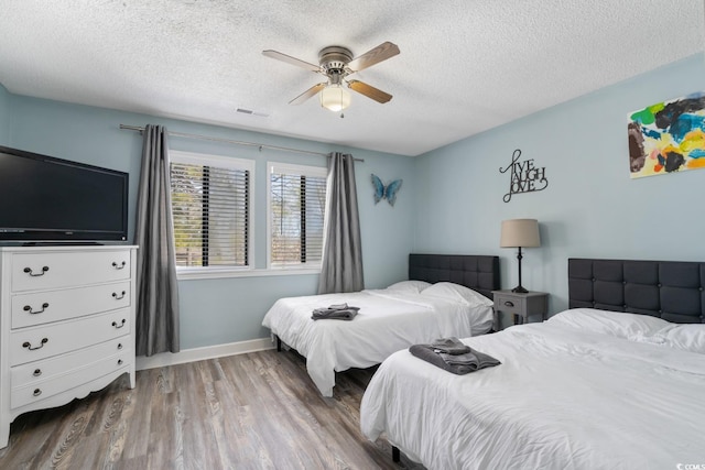 bedroom with hardwood / wood-style floors, a textured ceiling, and ceiling fan