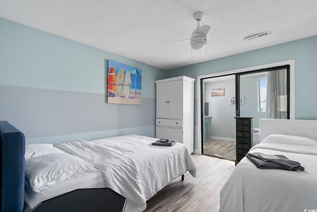 bedroom with ceiling fan, hardwood / wood-style flooring, and a textured ceiling