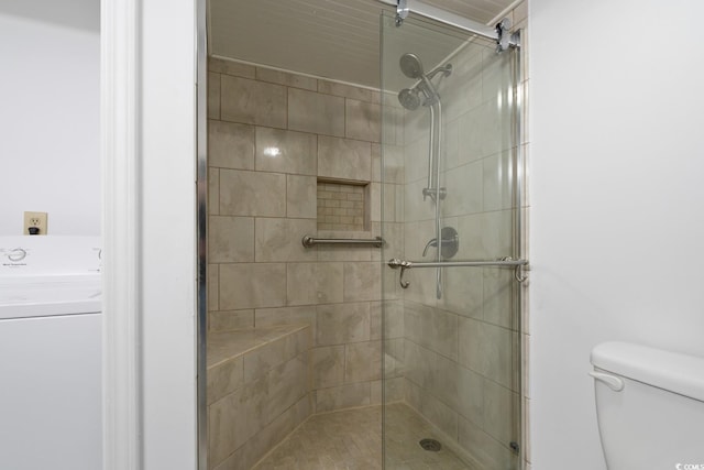 bathroom featuring toilet, washer / clothes dryer, and a shower with shower door