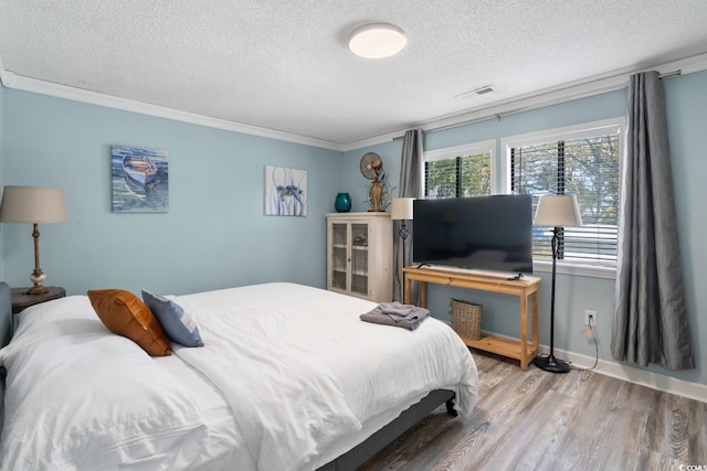 bedroom with hardwood / wood-style flooring, ornamental molding, and a textured ceiling