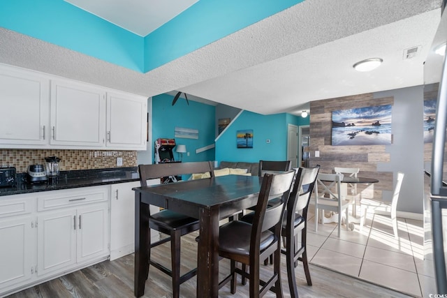 kitchen with white cabinetry, backsplash, light hardwood / wood-style flooring, and a textured ceiling