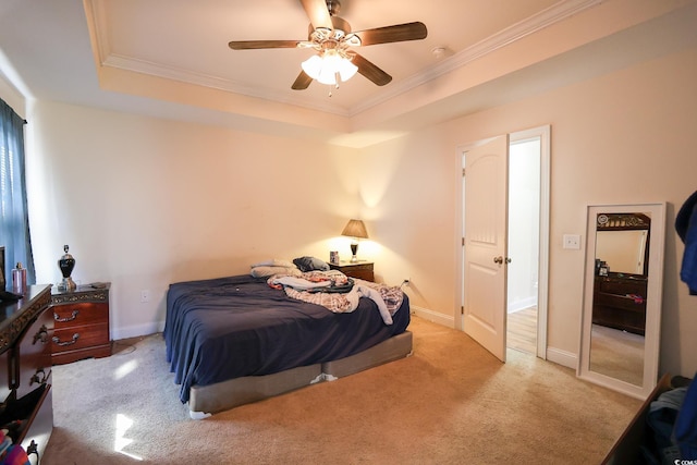 carpeted bedroom with ornamental molding, ceiling fan, a tray ceiling, and baseboards