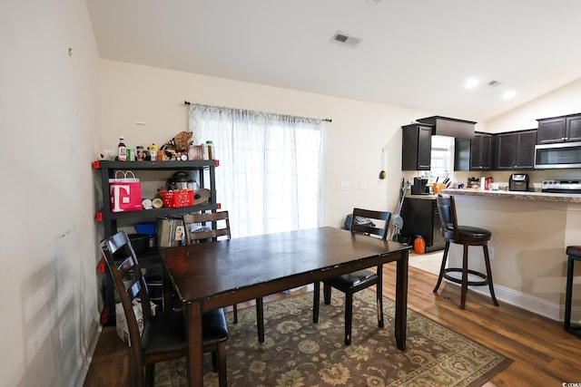 dining space with vaulted ceiling, wood finished floors, and visible vents