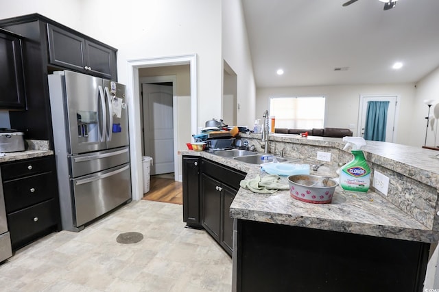 kitchen featuring a sink, light countertops, stainless steel fridge, and dark cabinets