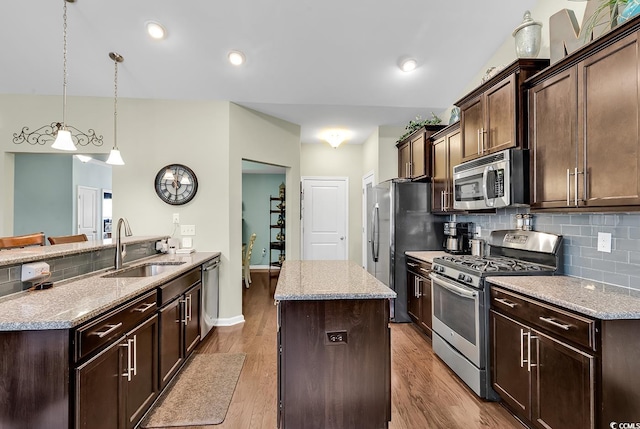 kitchen featuring pendant lighting, sink, a center island, dark brown cabinetry, and stainless steel appliances