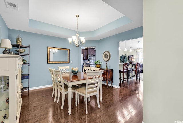 dining space with an inviting chandelier, dark hardwood / wood-style floors, and a raised ceiling