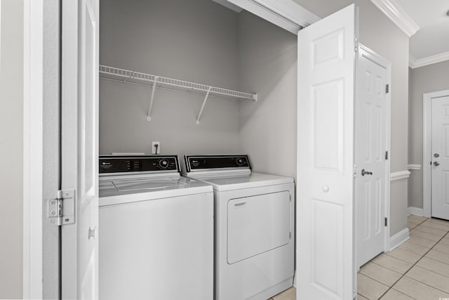 laundry area with light tile patterned floors, laundry area, ornamental molding, and washing machine and dryer