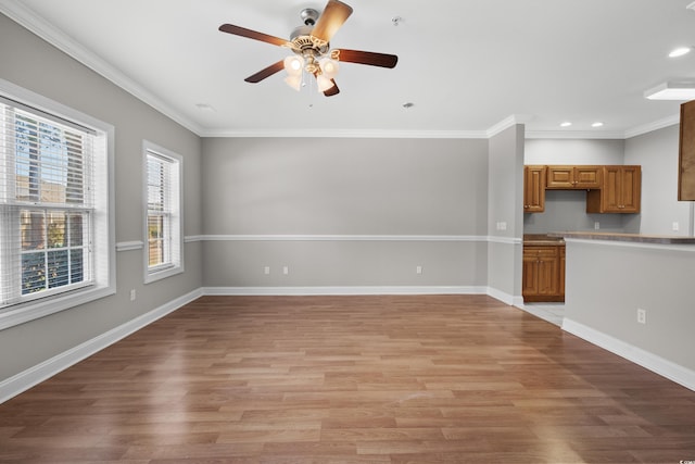 unfurnished living room with ornamental molding, light wood finished floors, and baseboards