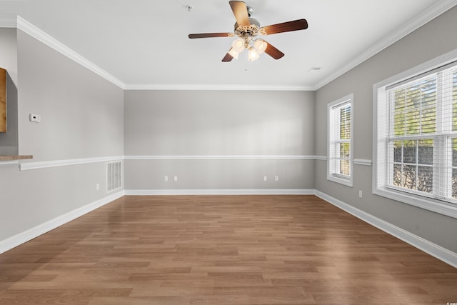 spare room featuring light wood finished floors, visible vents, baseboards, and ornamental molding