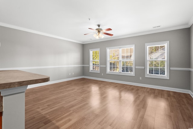 interior space with crown molding, visible vents, ceiling fan, wood finished floors, and baseboards