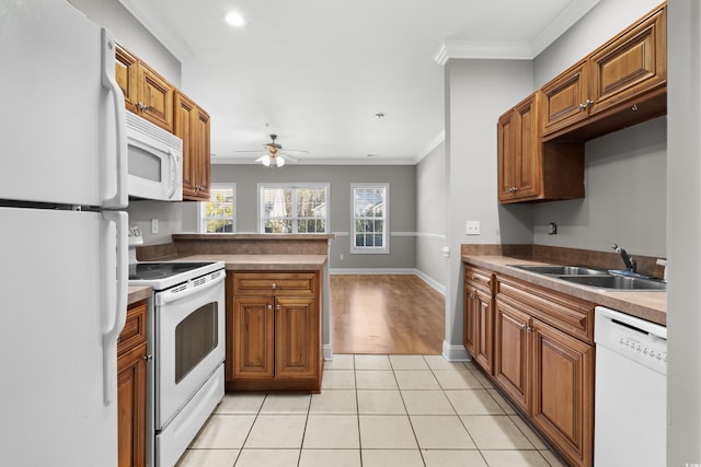 kitchen with white appliances, light tile patterned floors, ornamental molding, brown cabinets, and a sink