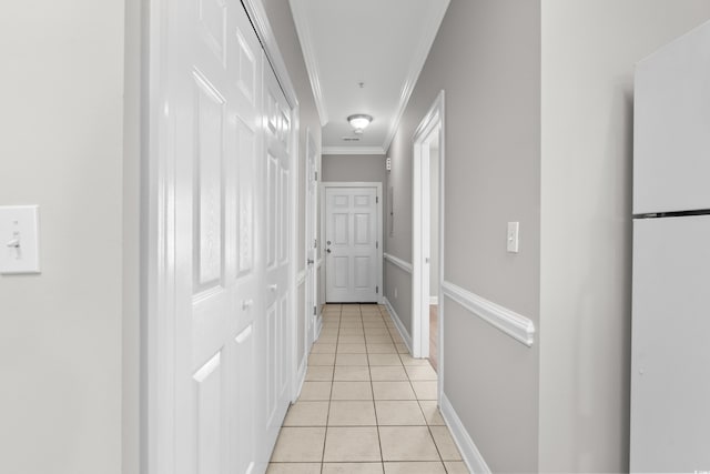 corridor featuring light tile patterned flooring, crown molding, and baseboards