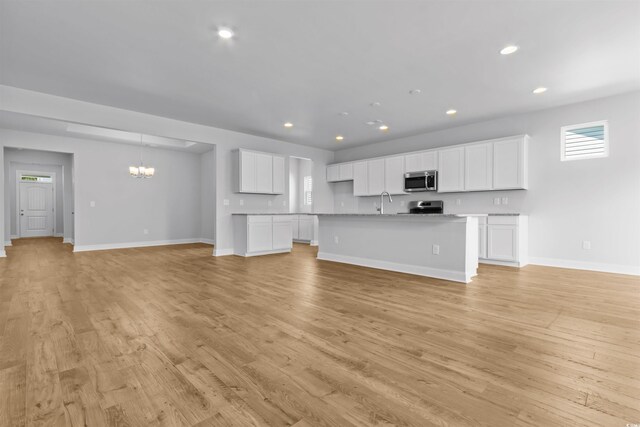 unfurnished dining area with a chandelier and light hardwood / wood-style floors