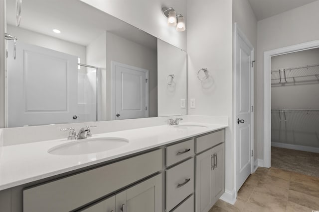bathroom featuring a spacious closet, walk in shower, double vanity, and a sink