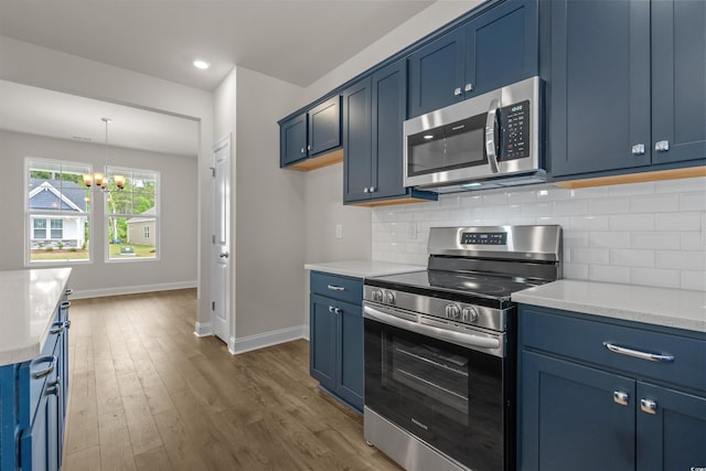 1212 NW Calabash Station Blvd, Calabash, NC 28467 - kitchen with decorative backsplash, a notable chandelier, blue cabinetry, baseboards, and appliances with stainless steel finishes