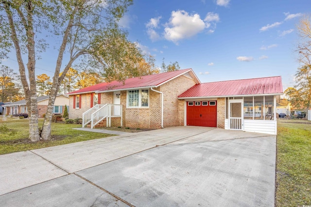 ranch-style home featuring a garage, a sunroom, and a front lawn