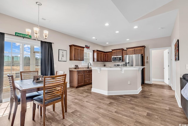 kitchen featuring a breakfast bar area, a kitchen island, pendant lighting, stainless steel appliances, and light hardwood / wood-style floors