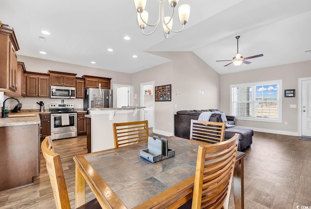 dining space with lofted ceiling, sink, ceiling fan with notable chandelier, and dark hardwood / wood-style floors