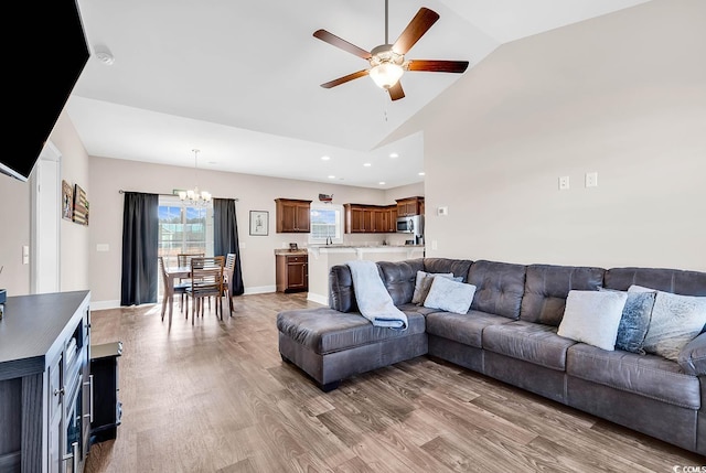 living room featuring hardwood / wood-style flooring, high vaulted ceiling, and ceiling fan with notable chandelier